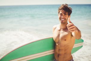 a man giving a thumbs up while holding a green surfboard